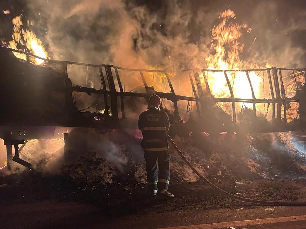 Carreta tomada pelas chamas e um bombeiro tentando apagar o fogo — Foto: Sargento Gonçalves/Corpo de Bombeiros de Mato Grosso