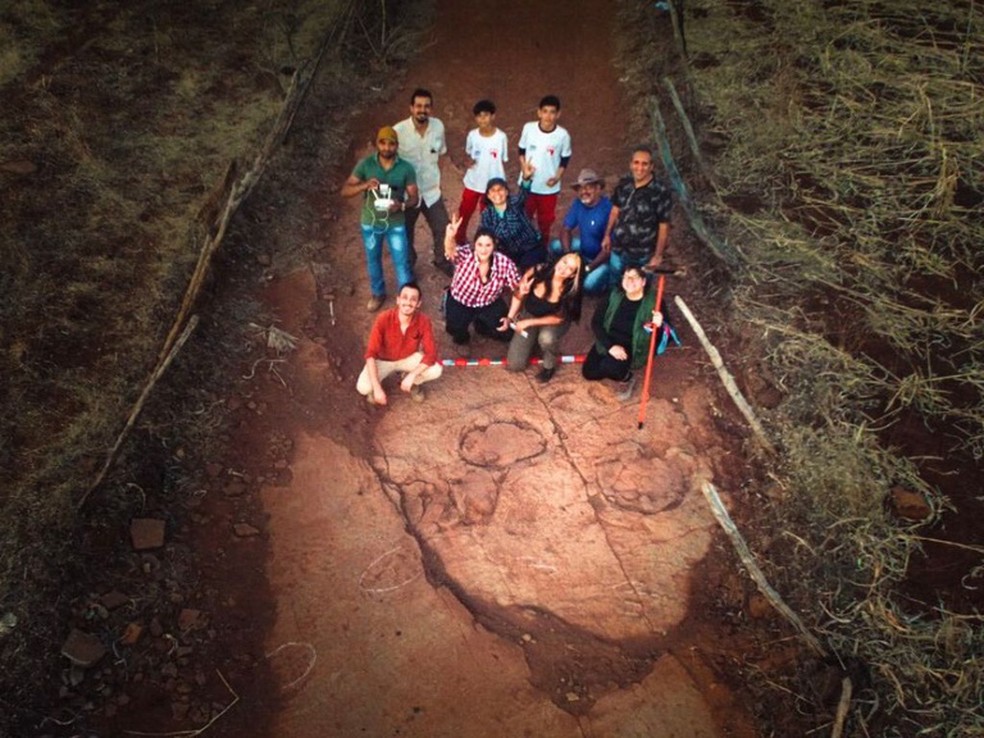 Equipe de pesquisadores ao lado das pegadas — Foto: Divulgação