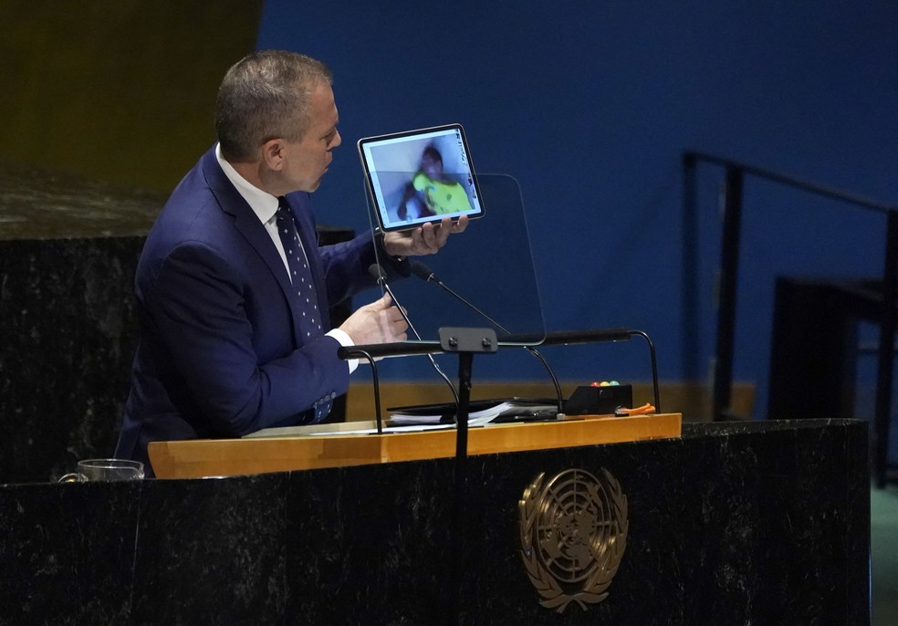 O embaixador de Israel na ONU, Gilad Erdan, usou tablet para mostrar supostas imagens e vídeos de vítimas de ataque terrorista do Hamas — Foto: Timothy A. Clary/AFP