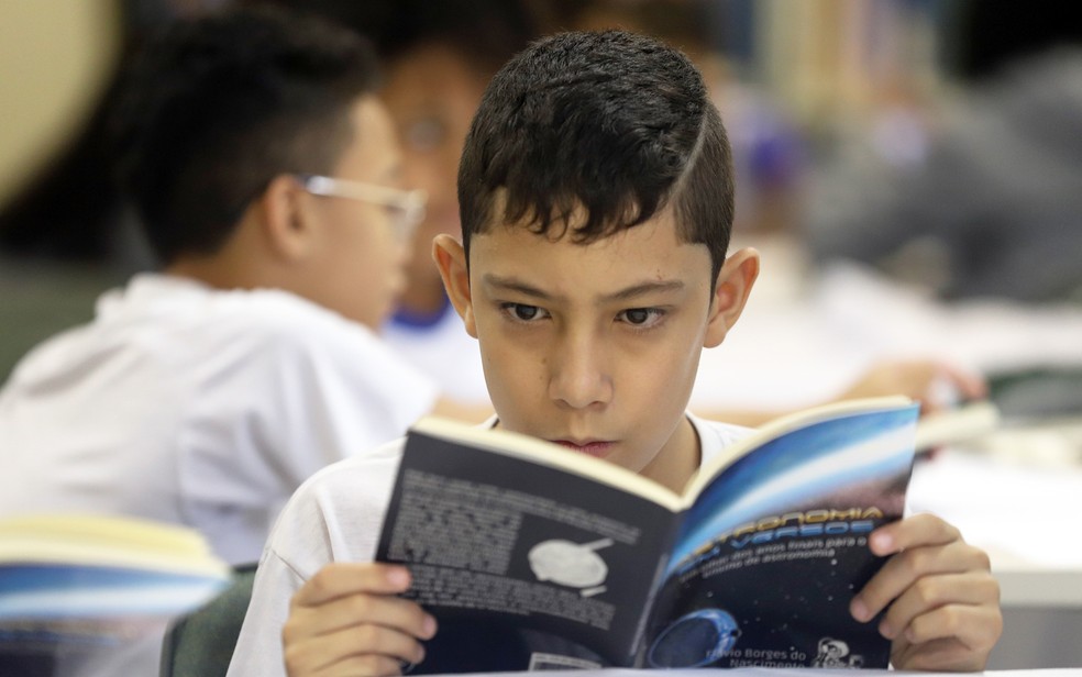 Estudante lê o livro de poesia 'Astronomia em versos', com poemas de estudantes de 11 anos da rede pública. — Foto: Divulgação/Governo do Estado de SP