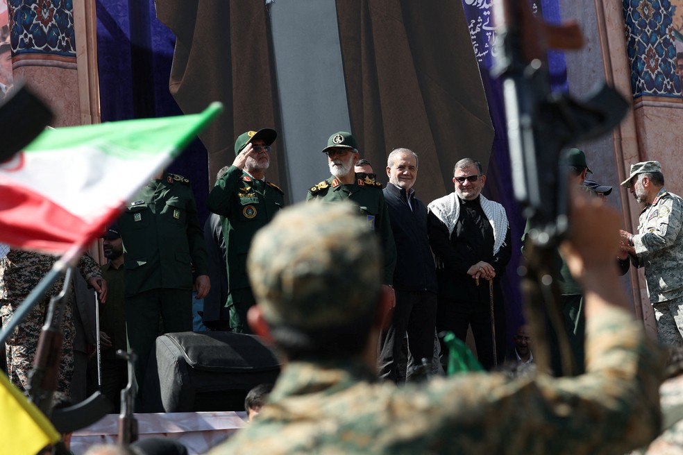 Soldados iranianos saúdam presidente do Irã, Masoud Pezeshkian (ao fundo, de roupa preta e sorrindo) durante desfile militar em Teerã, no Irã, em 18 de setembro de 2026. — Foto: Majid Asgaripour/Wana via REUTERS