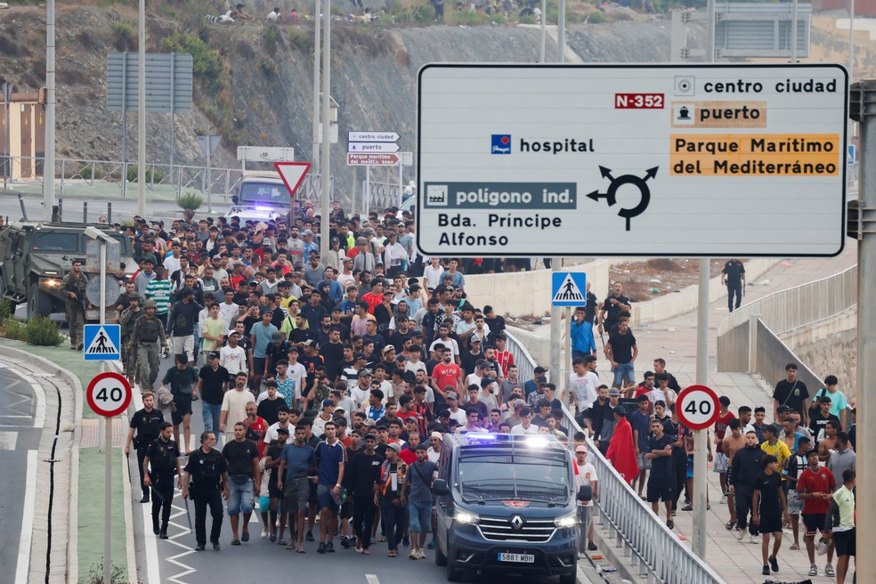 Policiais e soldados espanhóis escoltam um grande grupo de migrantes até a fronteira para retirá-los da Espanha — Foto: REUTERS/Jon Nazca