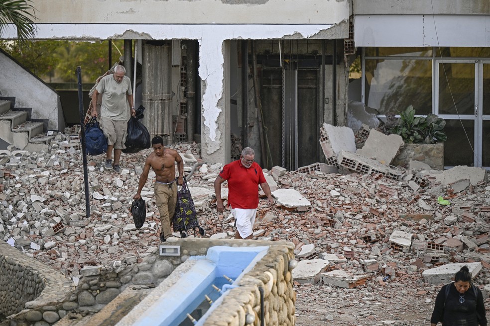 Pessoas carregam seus pertences para fora de um pr&eacute;dio danificado ap&oacute;s um terremoto em Catia La Mar, estado de La Guaira &mdash; Foto: FEDERICO PARRA / AFP