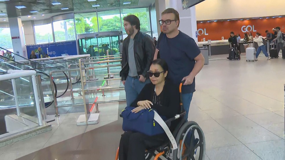 O diplomata Ibrahim Abdul Hak Neto empurra a cadeira de rodas da esposa, a também diplomata Ana Patrícia Neves Abdul Hak, no Aeroporto Santos Dumont — Foto: Betinho Casas Novas/ TV Globo