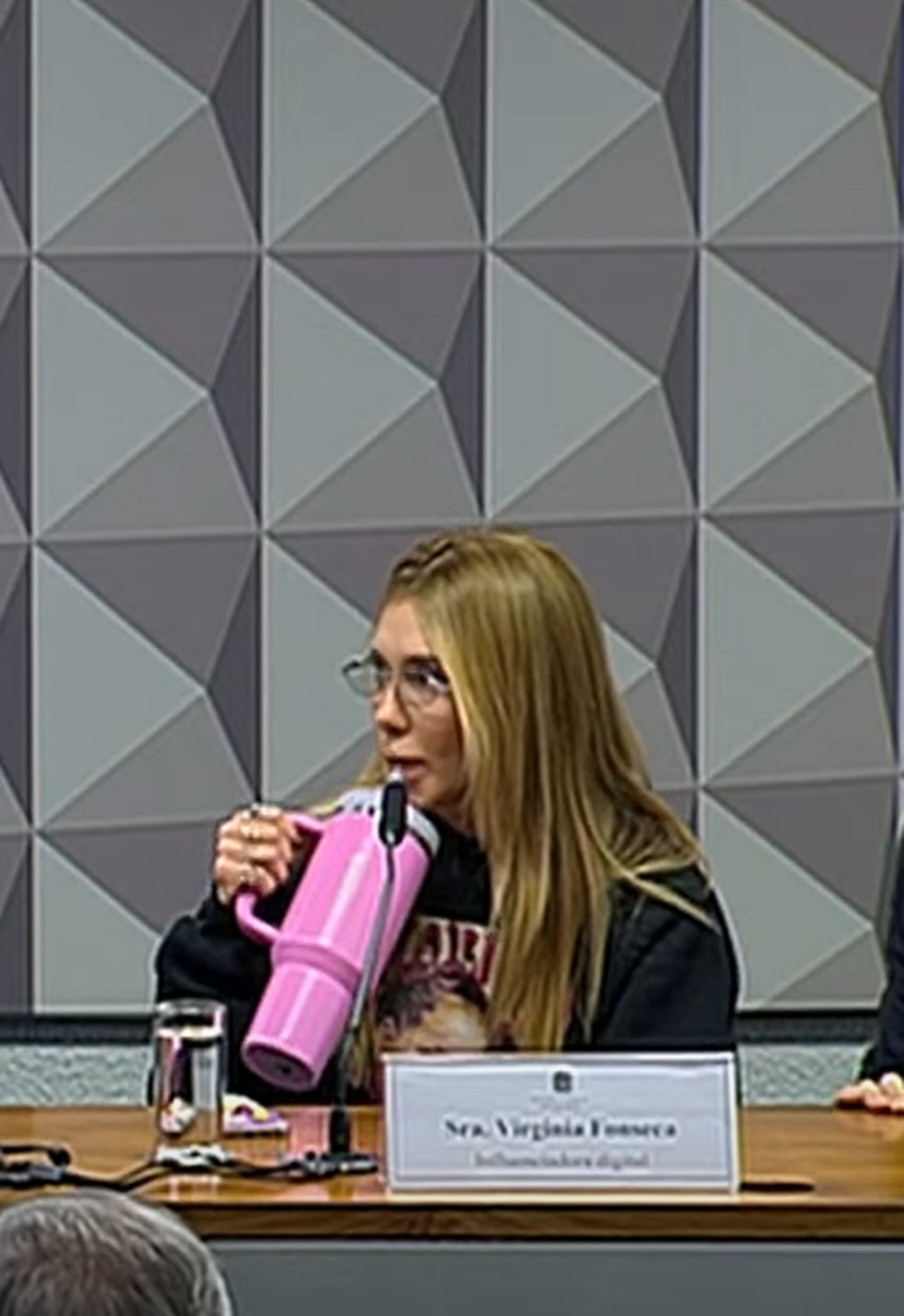 Virg&iacute;nia Fonseca vai &agrave; CPI de moletom com estampa da filha, Maria Flor, e copo Stanley rosa na mesa &mdash; Foto: Reprodu&ccedil;&atilde;o/YouTube