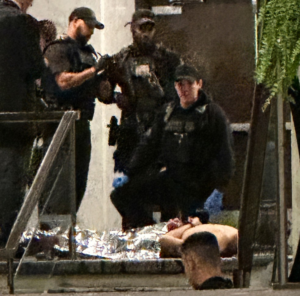 Homens do Serviço Secreto cercam pessoa deitada no chão após tiros disparados em jantar de correspondentes da Casa Branca com Donald Trump em Washington, nos EUA, em 25 de abril de 2026. — Foto: Alex Brandon/ AP