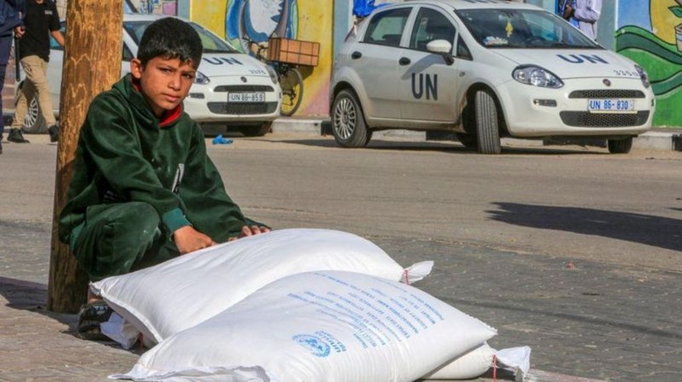 Criança ao lado de mantimentos dados pela agência da ONU em Gaza — Foto: GETTY IMAGES