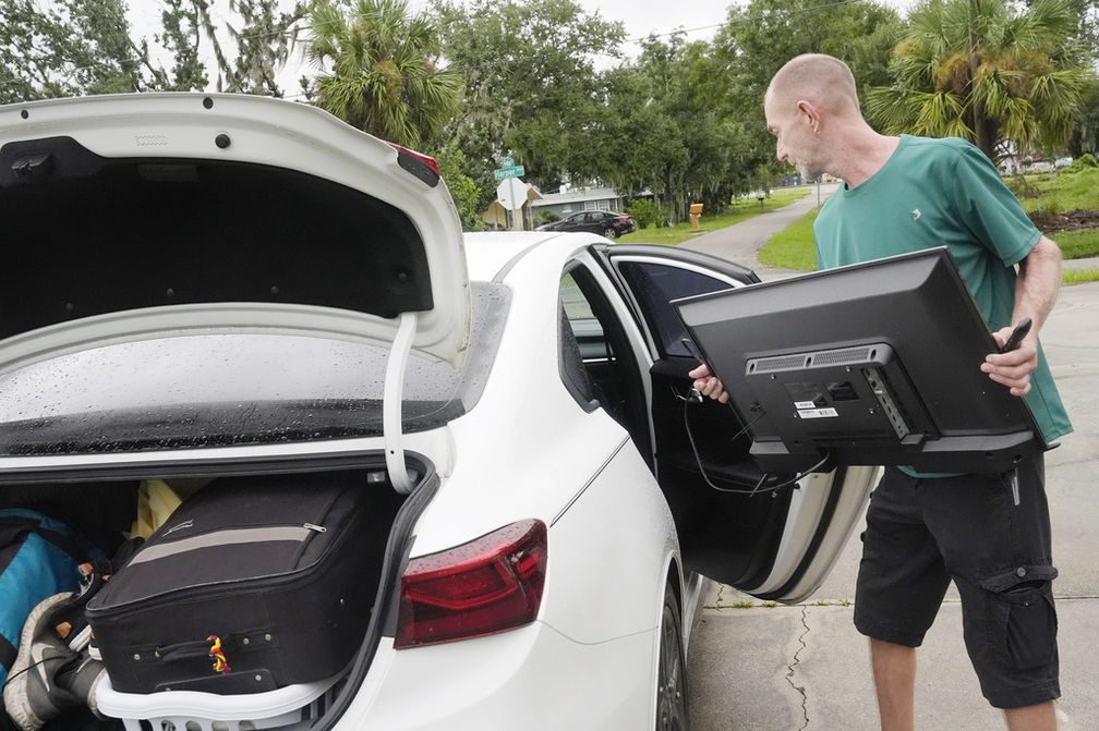 Homem guarda televisão ao deixar sua casa em Port Charlotte, na Flórida, antes da chegada do furacão Milton, em 9 de outubro de 2024. — Foto: Marta Lavandier/ AP