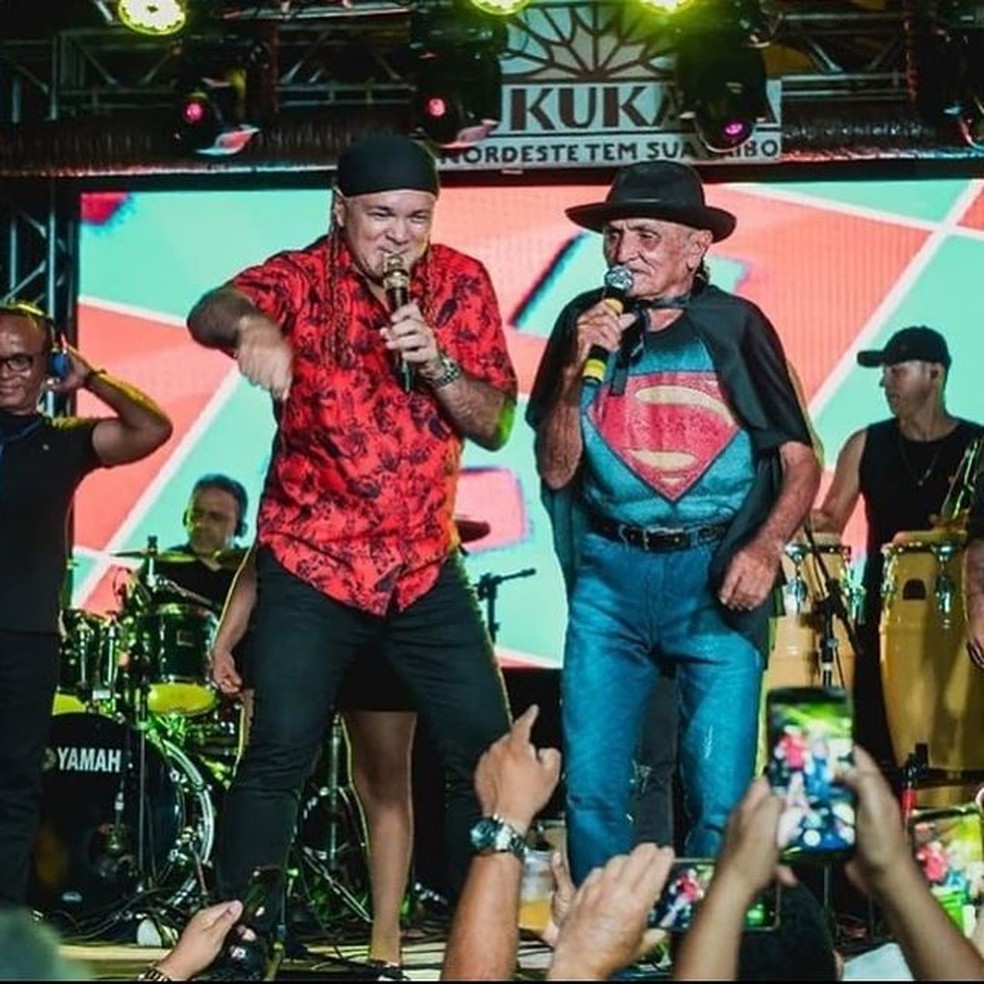 Chico Lopes, com camisa azul e chapéu vermelho, em participação de show da banda Aquarius, com Xampu. — Foto: Banda Aquarius/Divulgação