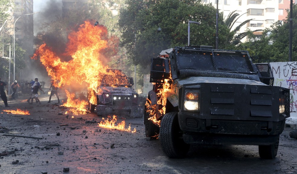 Veículos blindados da polícia foram incendiados em confronto em Santiago — Foto: Esteban Felt/AP