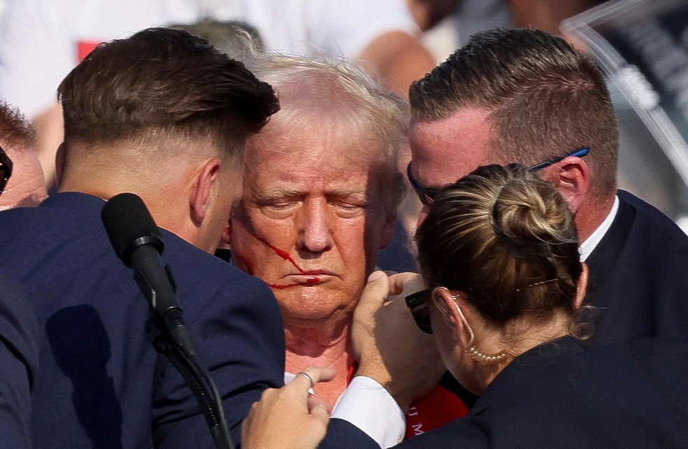 Donald Trump aparece com sangue no rosto e cercado por seguranças após tiros em comício — Foto: REUTERS/Brendan McDermid