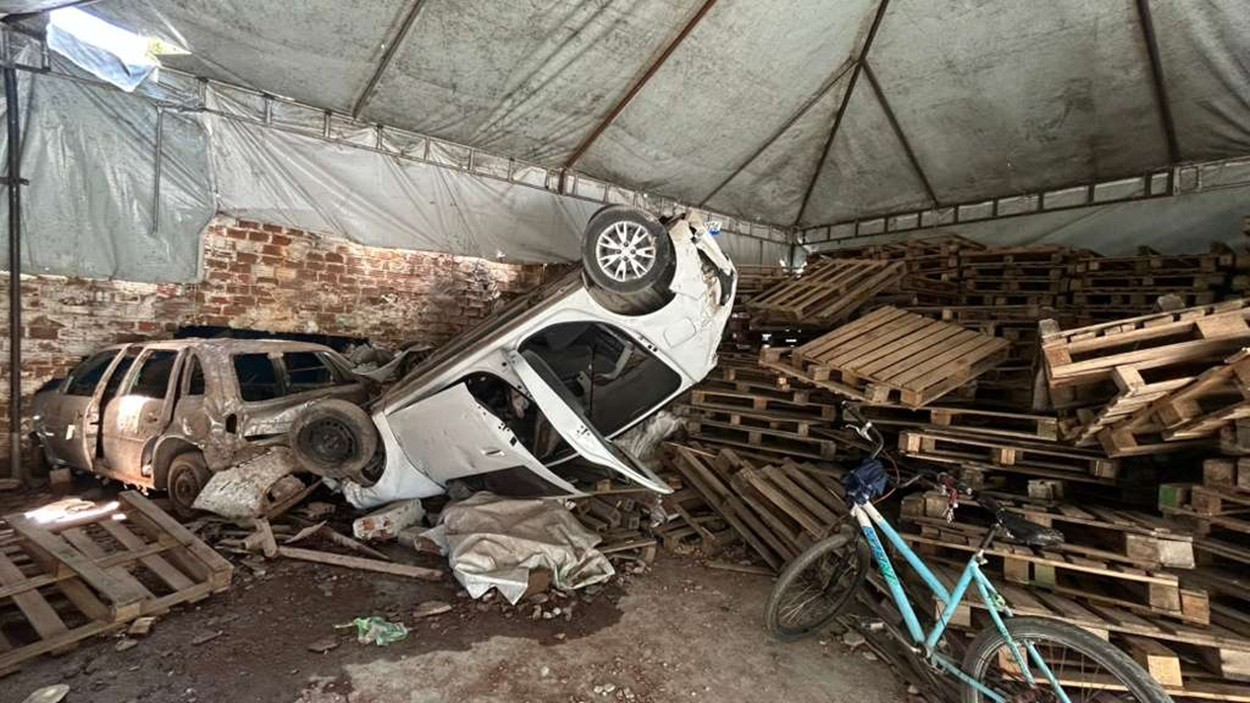 Carro capota, invade oficina e arrasta veículo para dentro de galpão; motorista ficou preso às ferragens