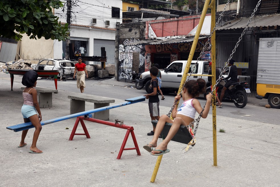Crianças brincam na Vila Cruzeiro, no Rio, ao lado de barricadas colocadas para conter avanço de policiais durante operação. — Foto: Tânia Rêgo/Agência Brasil