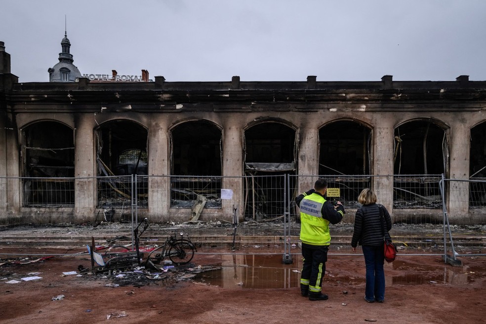 Policiais examinam prédio do escritório de turismo de Lyon, depredado nos protestos de sábado (17). — Foto: JEFF PACHOUD/AFP