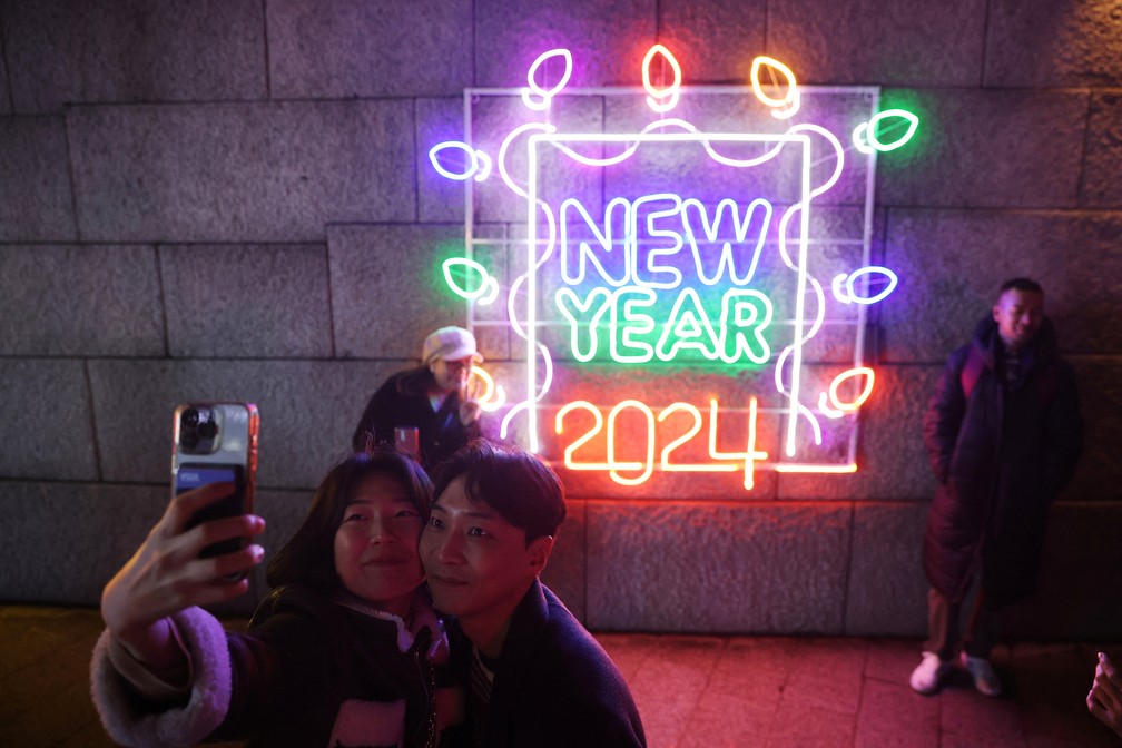 Casal tira foto diante de painel luminoso em festa em Seul, na Coreia do Sul, neste domingo (31) — Foto: Kim Hong-Ji/Reuters