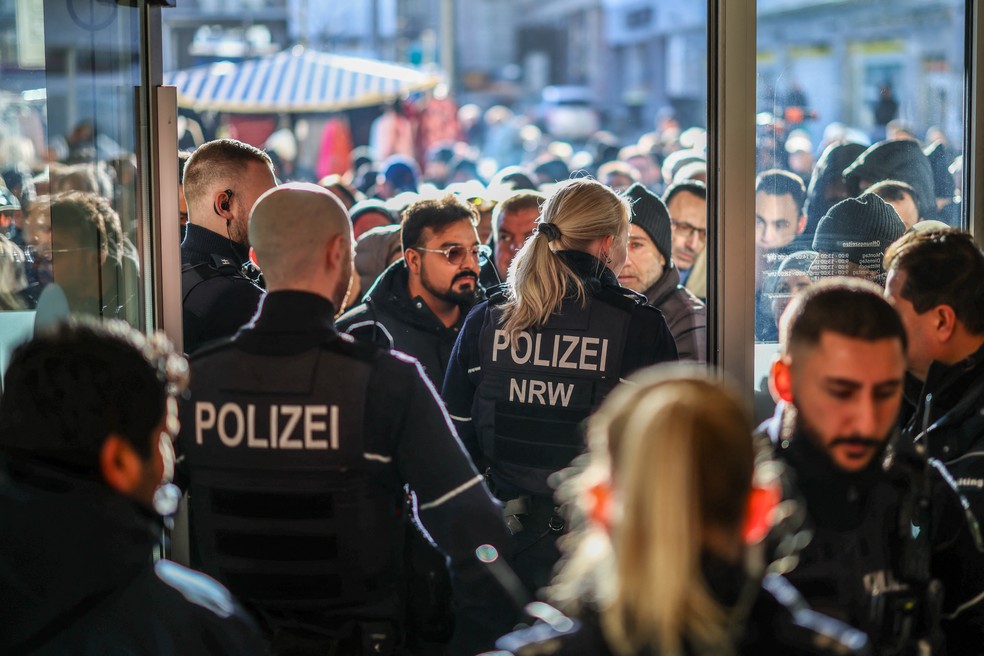 Policiais e clientes de banco se reuniram em frente a uma ag&ecirc;ncia do banco Sparkasse, em Gelsenkirchen, oeste da Alemanha, em 30 de dezembro de 2025, ap&oacute;s o banco ter sido assaltado. &mdash; Foto: Foto por CHRISTOPH REICHWEIN / DPA / AFP
