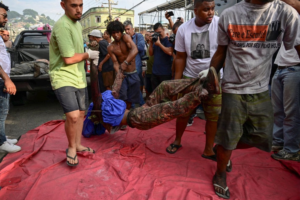ATENÇÃO, IMAGENS FORTES: corpo é colocado em praça no Complexo da Penha no dia seguinte à megaoperação no Rio — Foto: Pablo Porciuncula/AFP
