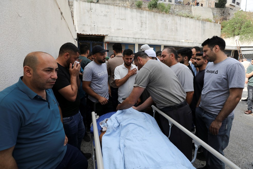 Palestinos se reúnem em torno do corpo de um homem morto durante um confronto com colonos israelenses — Foto: REUTERS/Nidal Eshtayeh