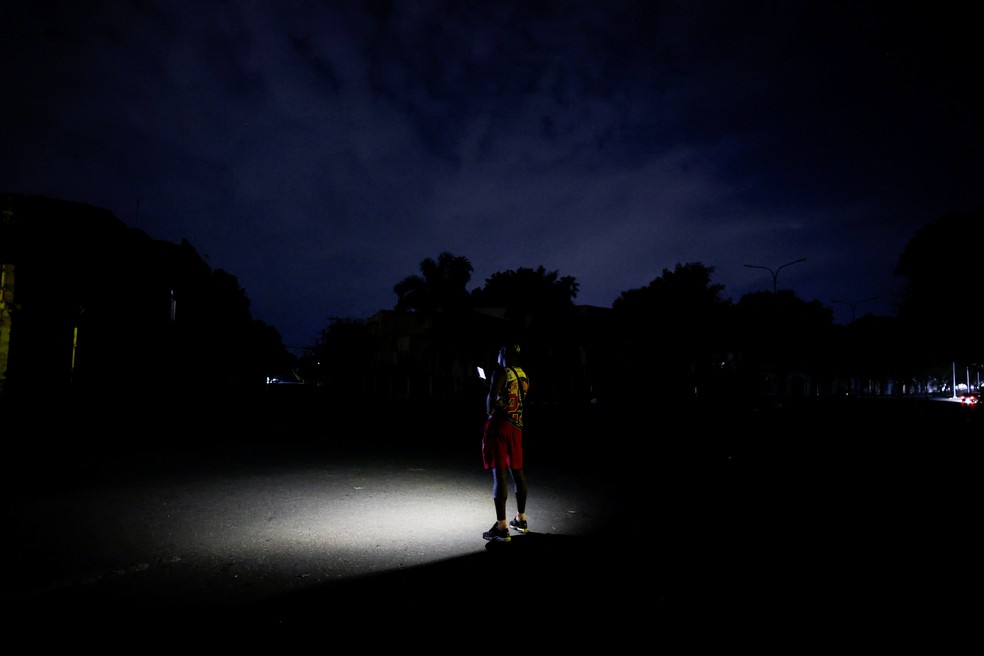Um homem espera por um táxi e usa seu celular como luz depois que a rede elétrica de Cuba entrou em colapso no final do domingo, mergulhando a ilha de cerca de 10 milhões de pessoas na escuridão, à medida que os apagões se tornam mais frequentes, em Havana, Cuba, 3 de agosto de 2026. — Foto: REUTERS/Norlys Perez
