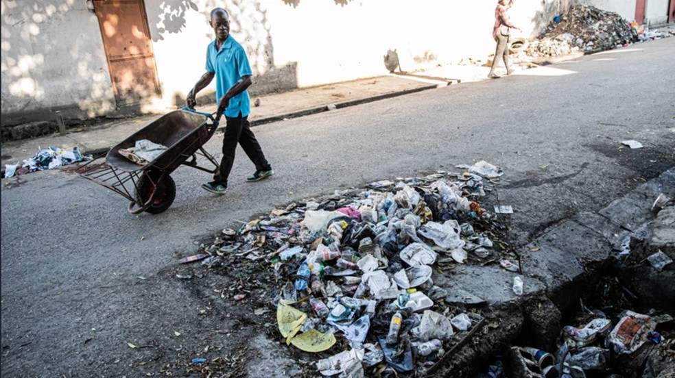 Homem passa perto de um cadáver atirado em uma vala de Porto Príncipe, em 19 de outubro de 2025 — Foto: Clarens Siffroy via BBC