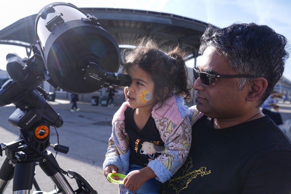 Pouco antes do eclipse, turistas observam o Sol através de telescópio posicionado na pista de automobilismo de Indianápolis, nos Estados Unidos — Foto: Michael Conroy/AP