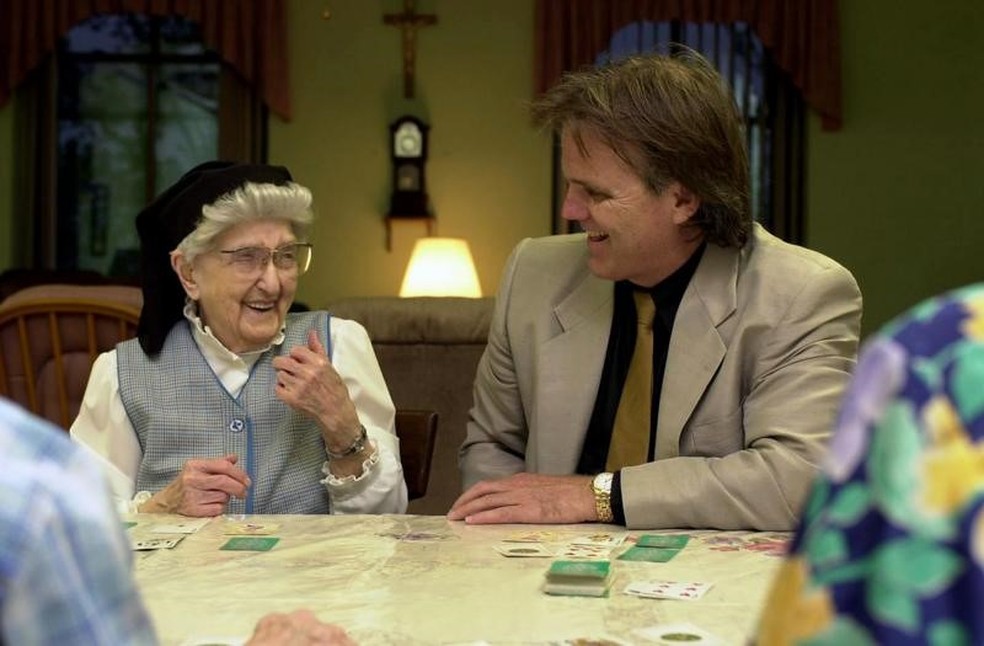 Irmã Esther, na foto com 106 anos, rindo ao lado de Snowdon, durante um jogo de cartas no convento — Foto: GETTY IMAGES via BBC