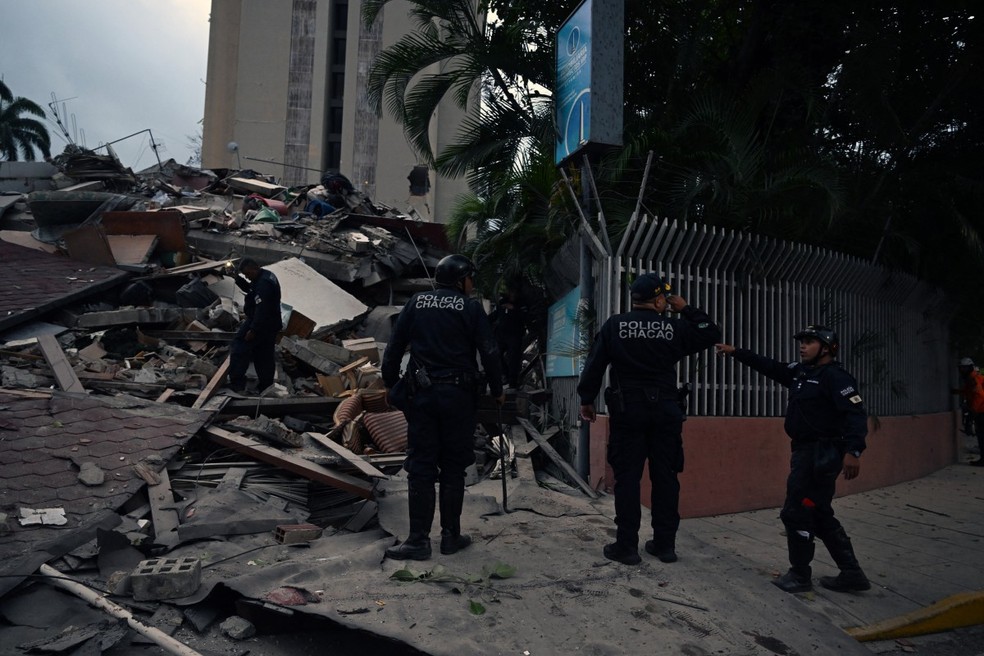 Policiais municipais ao lado dos escombros de uma estrutura que desabou após um terremoto em Caracas, em 24 de junho de 2026 — Foto: Juan Barreto/AFP