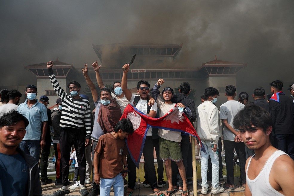 Manifestantes comemoram com bandeira do Nepal após entrar em complexo do Parlamento nepalês durante protesto contra o governo em 9 de setembro de 2025. — Foto: REUTERS/Adnan Abidi