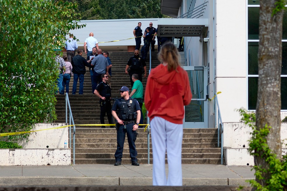 Um estudante observa enquanto policiais de Tacoma investigam o local após várias pessoas ficarem feridas na Foss High School. — Foto: John Froschauer / AP