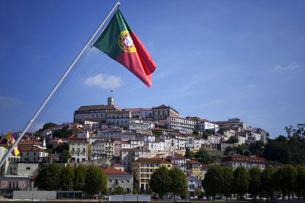 Uma bandeira portuguesa pendurada em uma ponte sobre o rio Mondego com o prédio principal da Universidade de Coimbra ao fundo, no topo da colina, em Coimbra, Portugal, sexta-feira, 23 de setembro de 2022. — Foto: AP Photo/Armando Franca