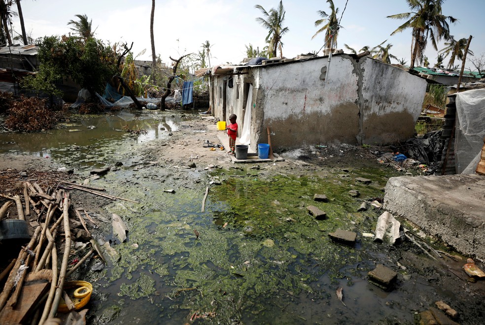 Criança ao lado de poças de água parada em Beira, Moçambique. — Foto: Mike Hutchings/Reuters