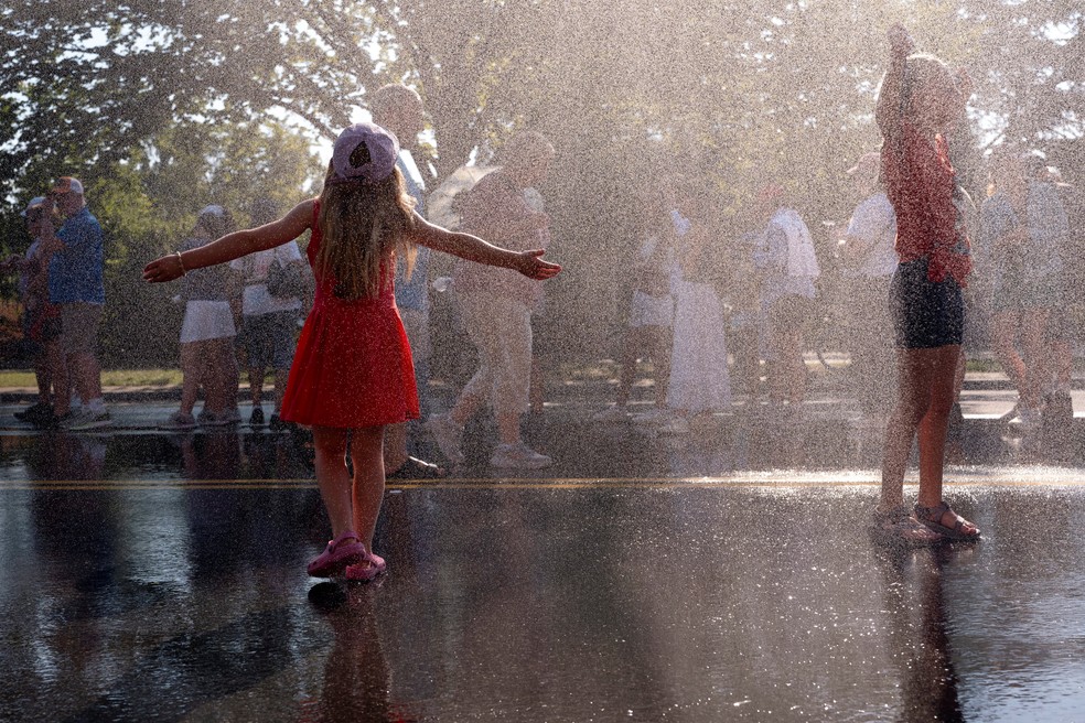Crianças se refrescam em jatos de água após o fechamento temporário da Great American State Fair devido ao calor, no National Mall, em Washington. — Foto: Reuters