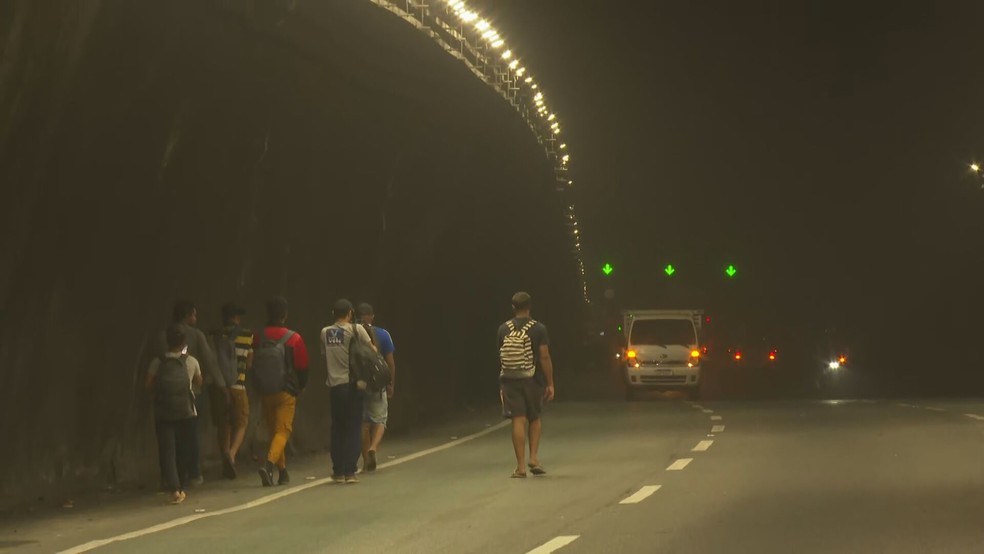 Passageiros de ônibus andam a pé no Túnel da Covanca após incêndio — Foto: Betinho Casas Novas/TV Globo