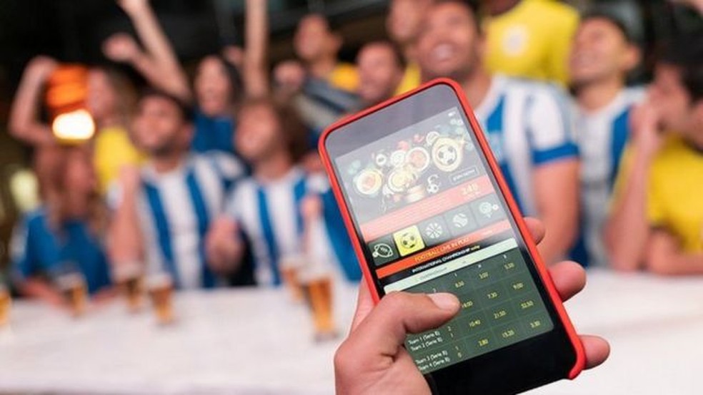 Homem com smartphone, jogador fazendo apostas de futebol. vício em jogos de  azar no celular, aplicativo de apostas esportivas, previsão de resultados  de partidas de futebol.
