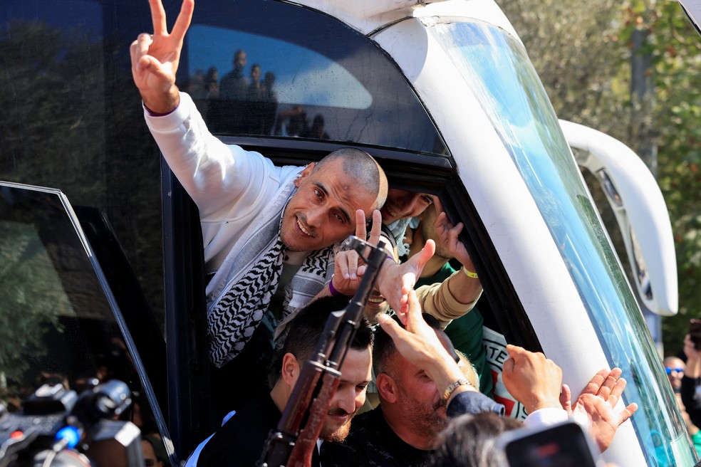 Prisioneiro palestino acena de dentro de ônibus após ser libertado de prisão israelense — Foto: Mussa Qawasma/Reuters