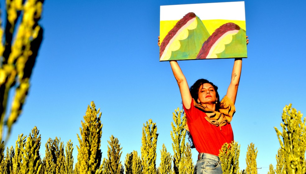 Renata Egreja segura uma de suas obras, em meio ao cenário da fazenda em Ipaussu (SP), onde mora e mantém seu ateliê — Foto: Roberta Tossi/Divulgação
