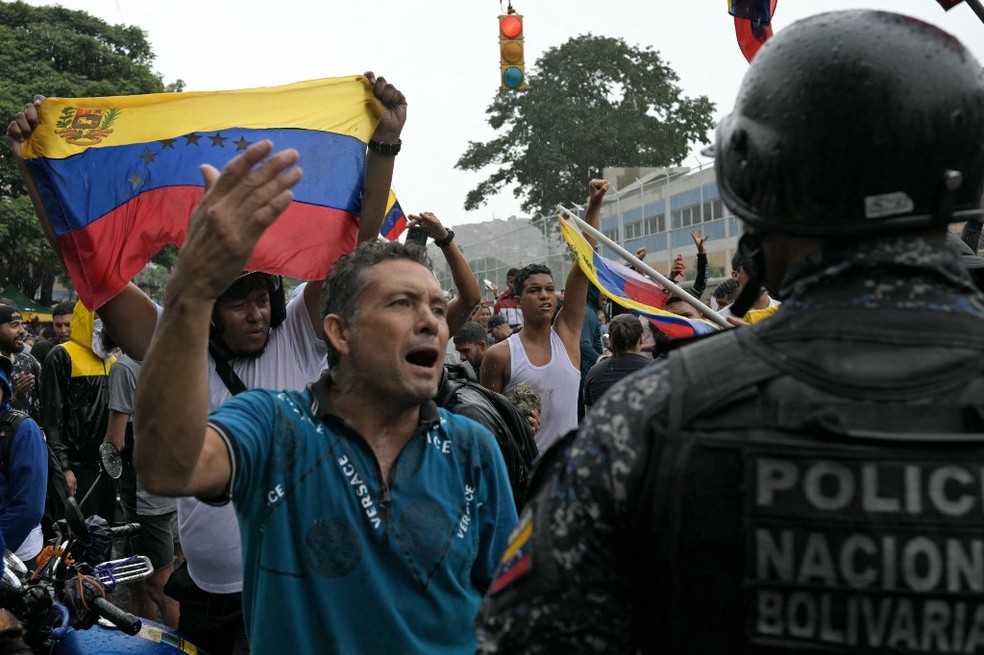 Policial observa manifestante contra o resultado da eleição na Venezuela — Foto: Yuri Cortez/AFP