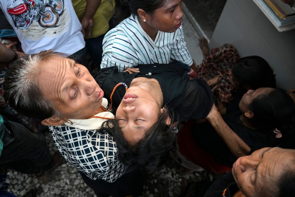 Jovem desmaia durante funeral de nobre em Sumba, na Indon&eacute;sia &mdash; Foto: Bay Ismoyo/AFP