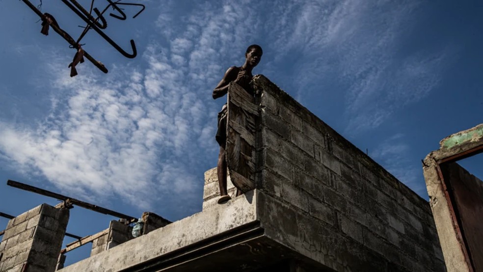 Homem observa de pé, no telhado de uma casa destruída no bairro de Solino, em Porto Príncipe (Haiti), no dia 17 de fevereiro de 2026 — Foto: Clarens Siffroy via BBC