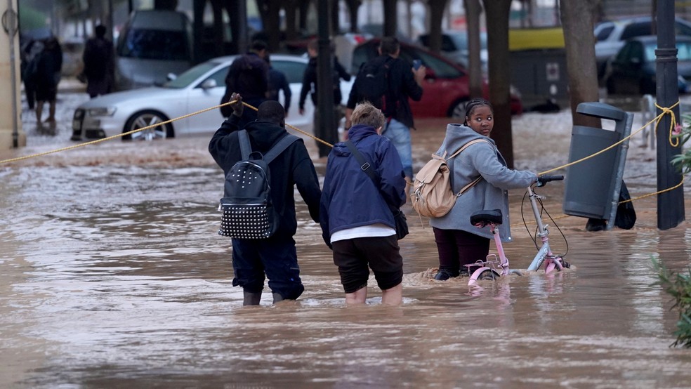 Pessoas caminham pelas ruas inundadas em Valência — Foto: Alberto Saiz / AP Photo