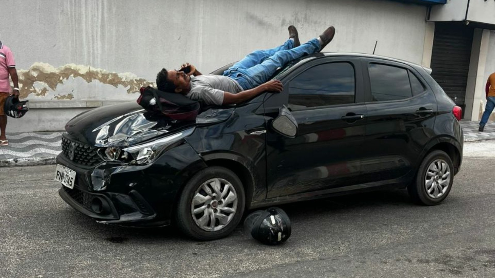 Motociclista cai sobre capô de carro após acidente e usa celular enquanto aguarda socorro; vídeo