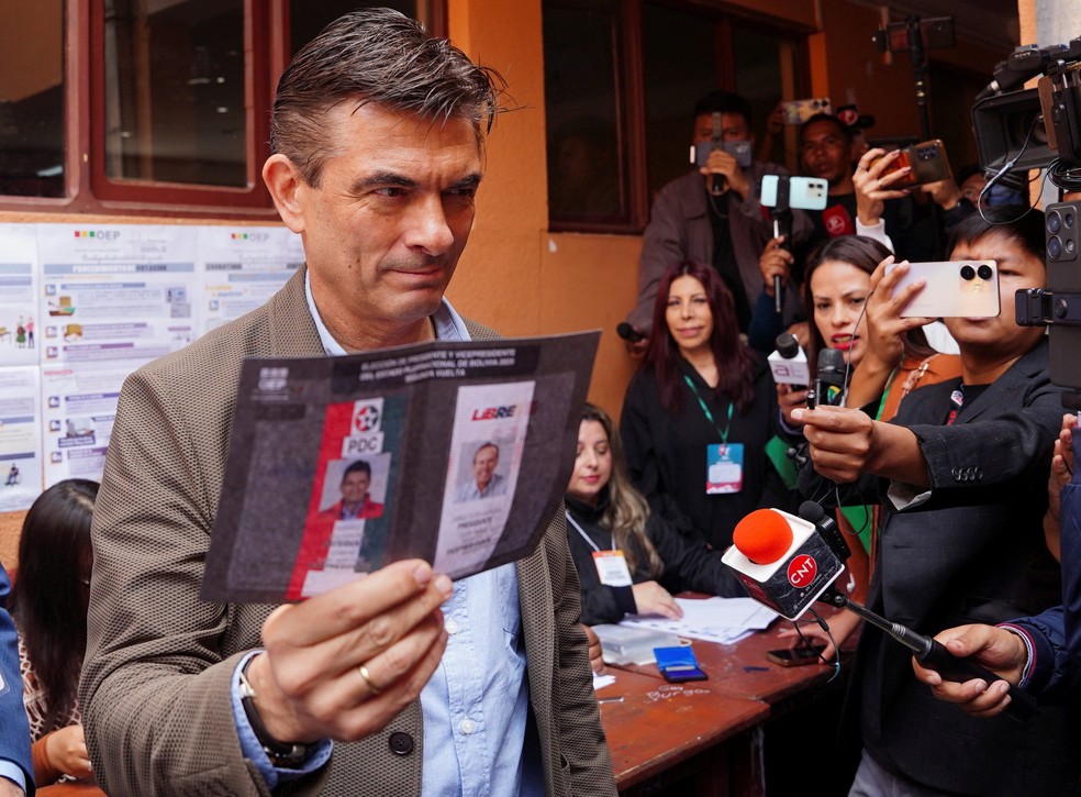 O senador e candidato Rodrigo Paz, do Partido Democrata Cristão, mostra sua cédula de votação antes de votar neste domingo (19) — Foto: REUTERS/Sara Aliaga