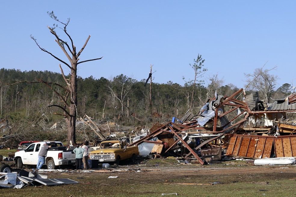 Moradores procuram pertences entre os destroços após a passagem de um tornado que deixou duas pessoas mortas neste domingo (16) em Plantersville, Alabama. — Foto: AP/Butch Dill