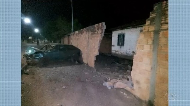 Batida entre carro e moto derruba muro de casa e deixa duas pessoas feridas
