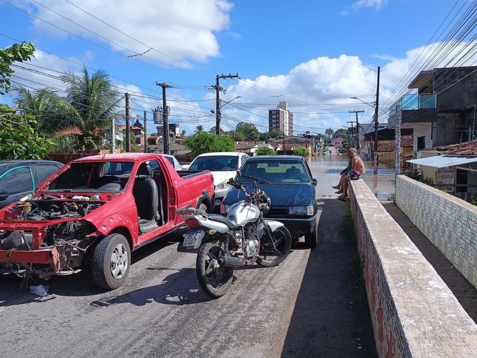 Veículos que estavam em oficina mecânica alagada são estacionados em ponte, em Santa Rita, PB — Foto: Ewerton Correia/TV Cabo Branco