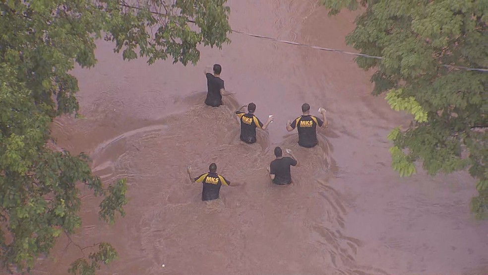 Pessoas circulando em meio à água suja do alagamento em Santo André, na Grande SP — Foto: Reprodução/TV Globo