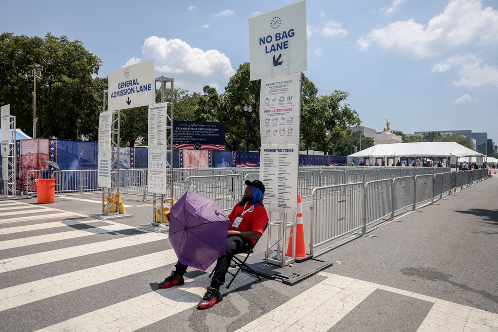 Um funcionário usa um guarda-chuva para se proteger do sol durante período de calor extremo na região de Washington, na entrada da Great American State Fair. — Foto: Reuters