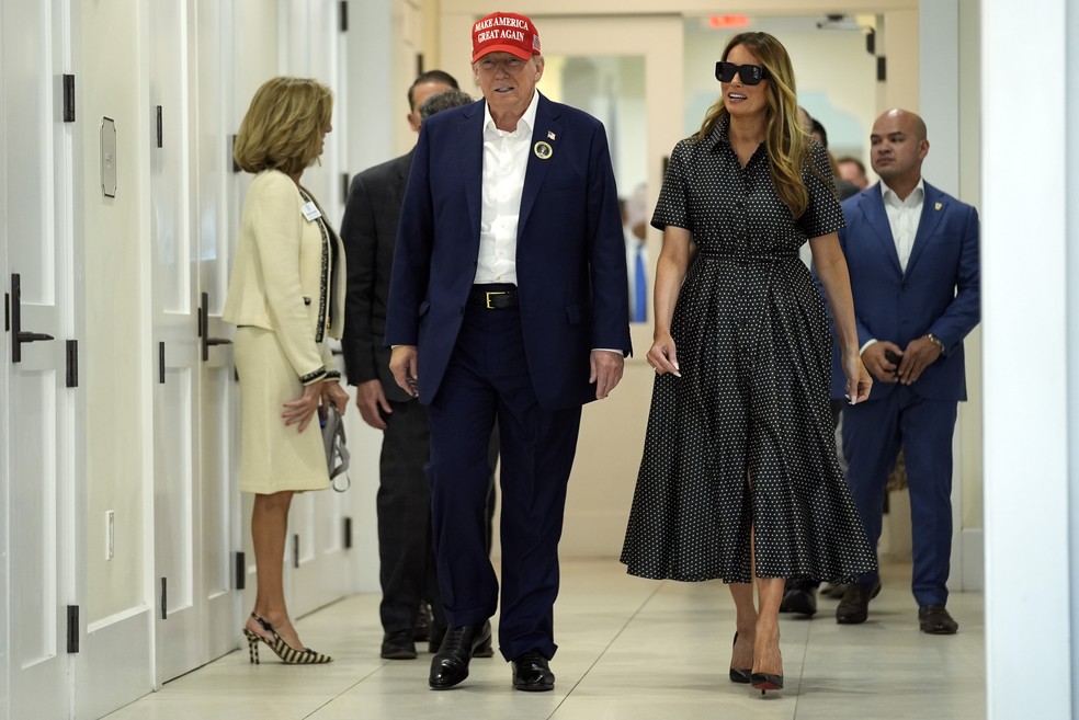 O candidato presidencial republicano e ex-presidente Donald Trump caminha ao lado da ex-primeira-dama Melania Trump após registrar seu voto no Centro Recreativo Morton and Barbara Mandel, em Palm Beach, Flórida (5/11) — Foto: Evan Vucci/AP
