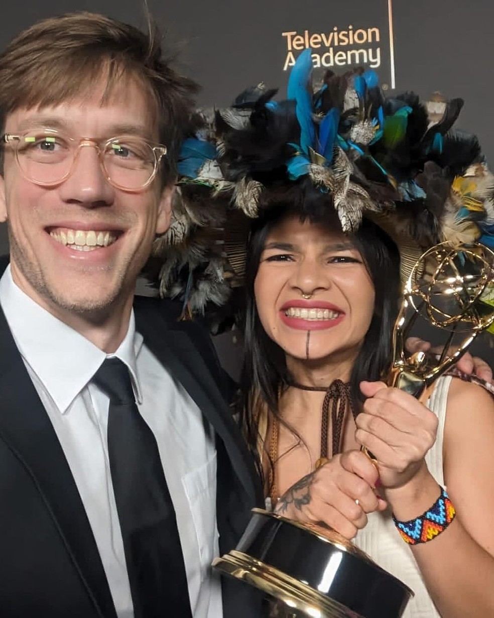 Ativista e produtora do documentário Txaí Suruí e o diretor Alex Pritz segurando a estatueta do Emmy  — Foto: Reprodução/ Rede Sociais