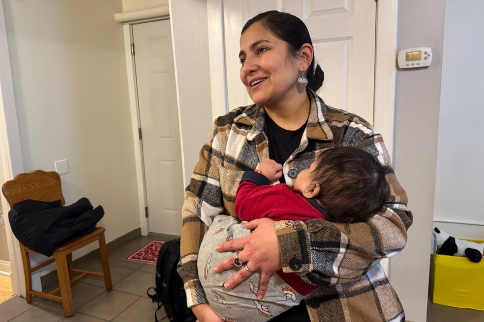 A voluntária Feliza Martínez segura um bebê cuja mãe foi presa por agentes do ICE, em janeiro de 2026. Ela abrigou os filhos da imigrante em sua casa. — Foto: Jack Brook/ AP